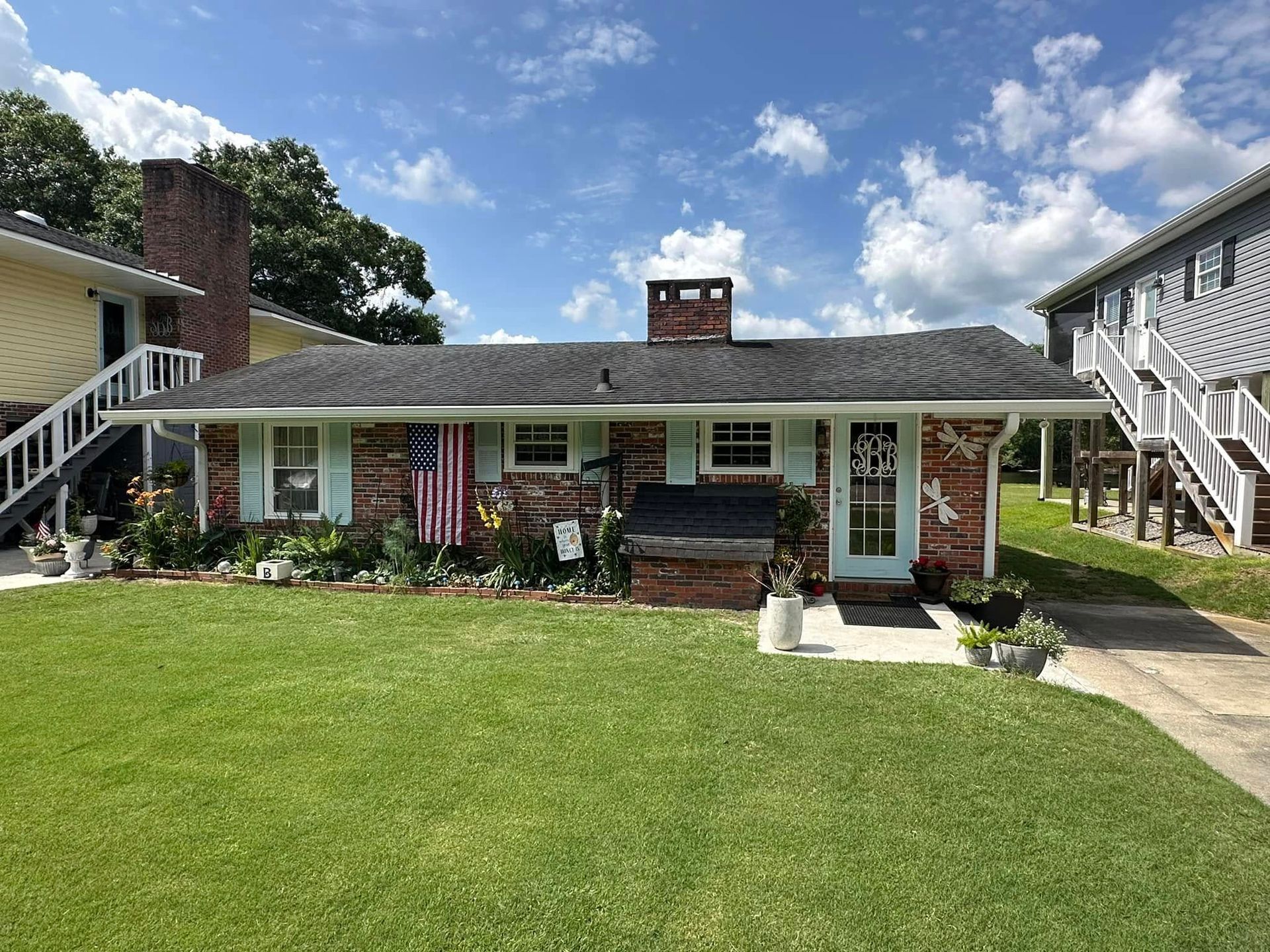 Single-story brick house with white trim, front lawn, and a clear blue sky