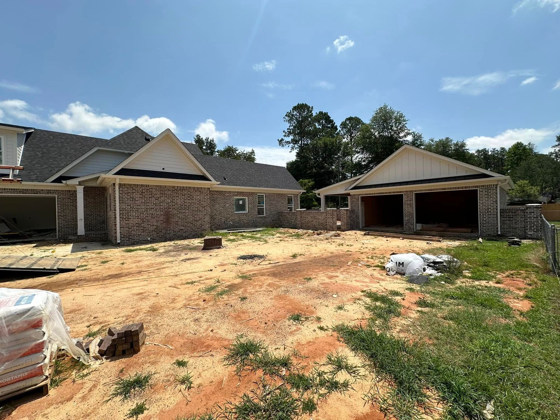 Two brick houses with unfinished yards under a bright blue sky