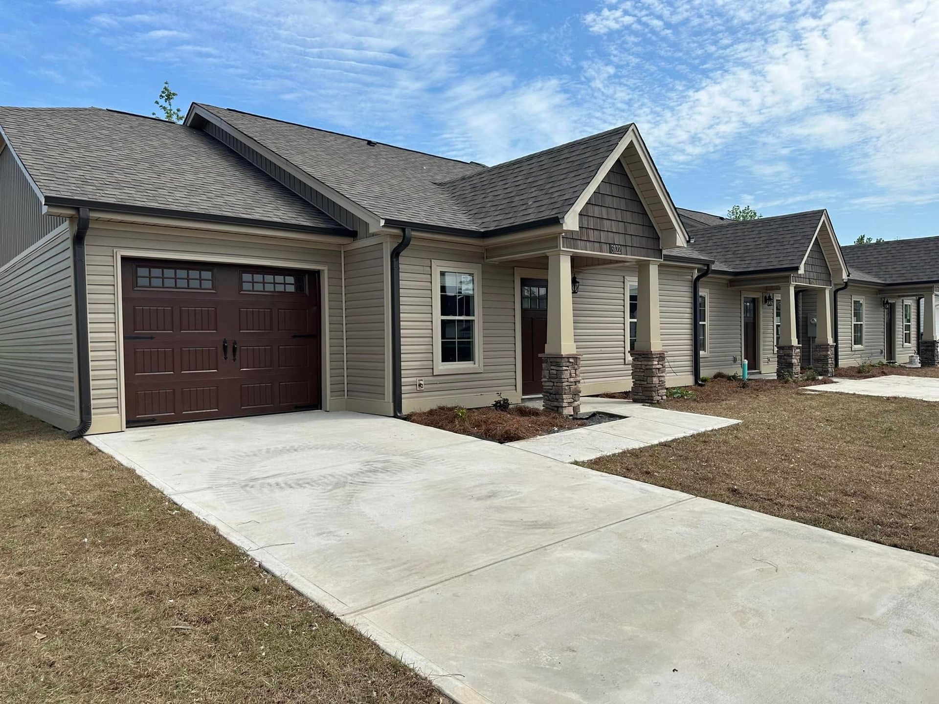 New suburban house with a single-car garage, concrete driveway, and stone-accented front entry