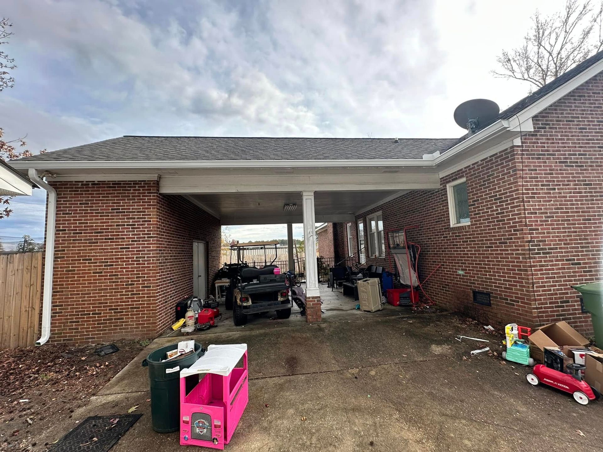 Brick carport with cluttered toys and items, including a pink toy car in the foreground.
