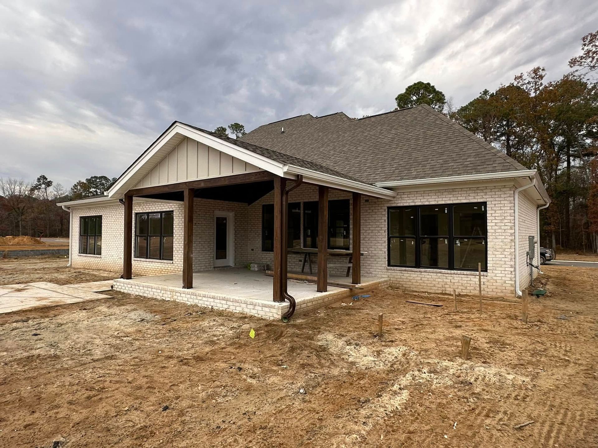 New single-story brick house with a gray roof and covered front porch on a bare lot