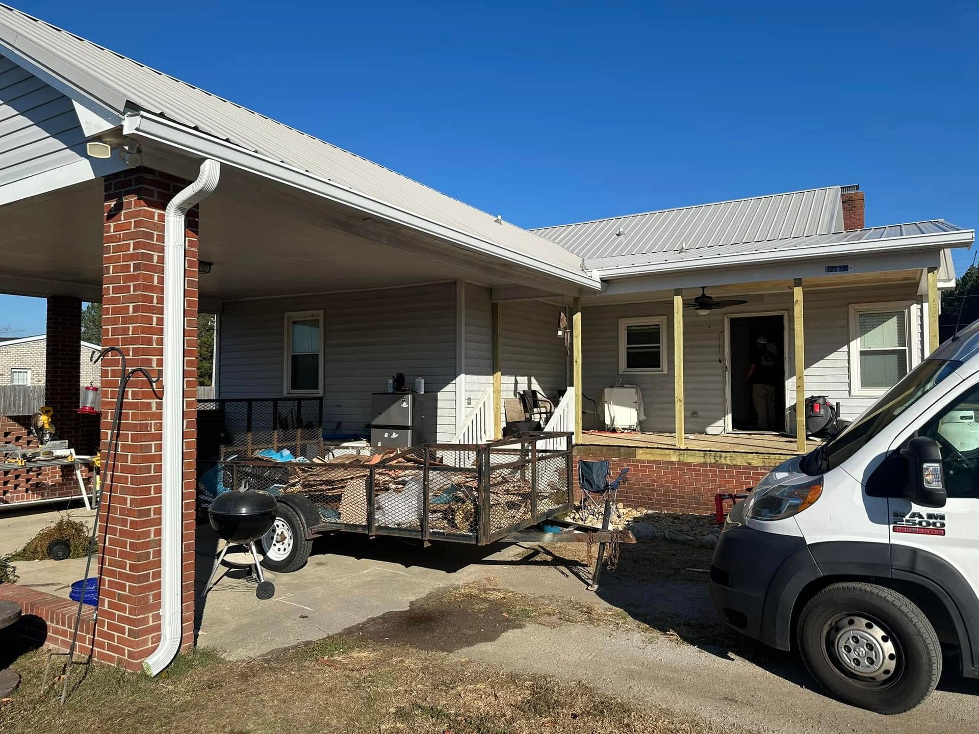 Front porch of a house with furniture, a motorcycle, and a white van parked beside it.