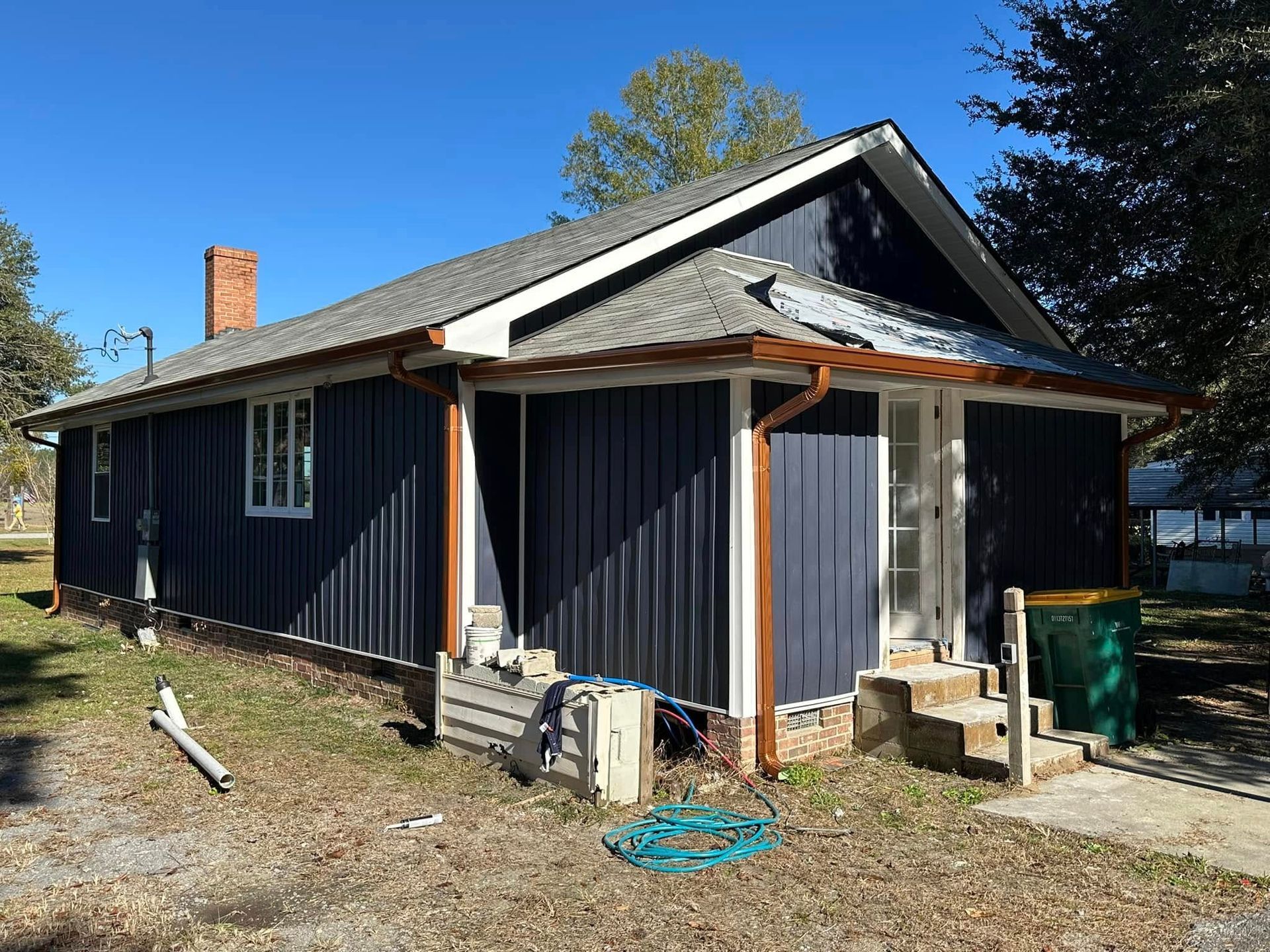 Small blue house with white trim and a porch, seen from the front on a sunny day.