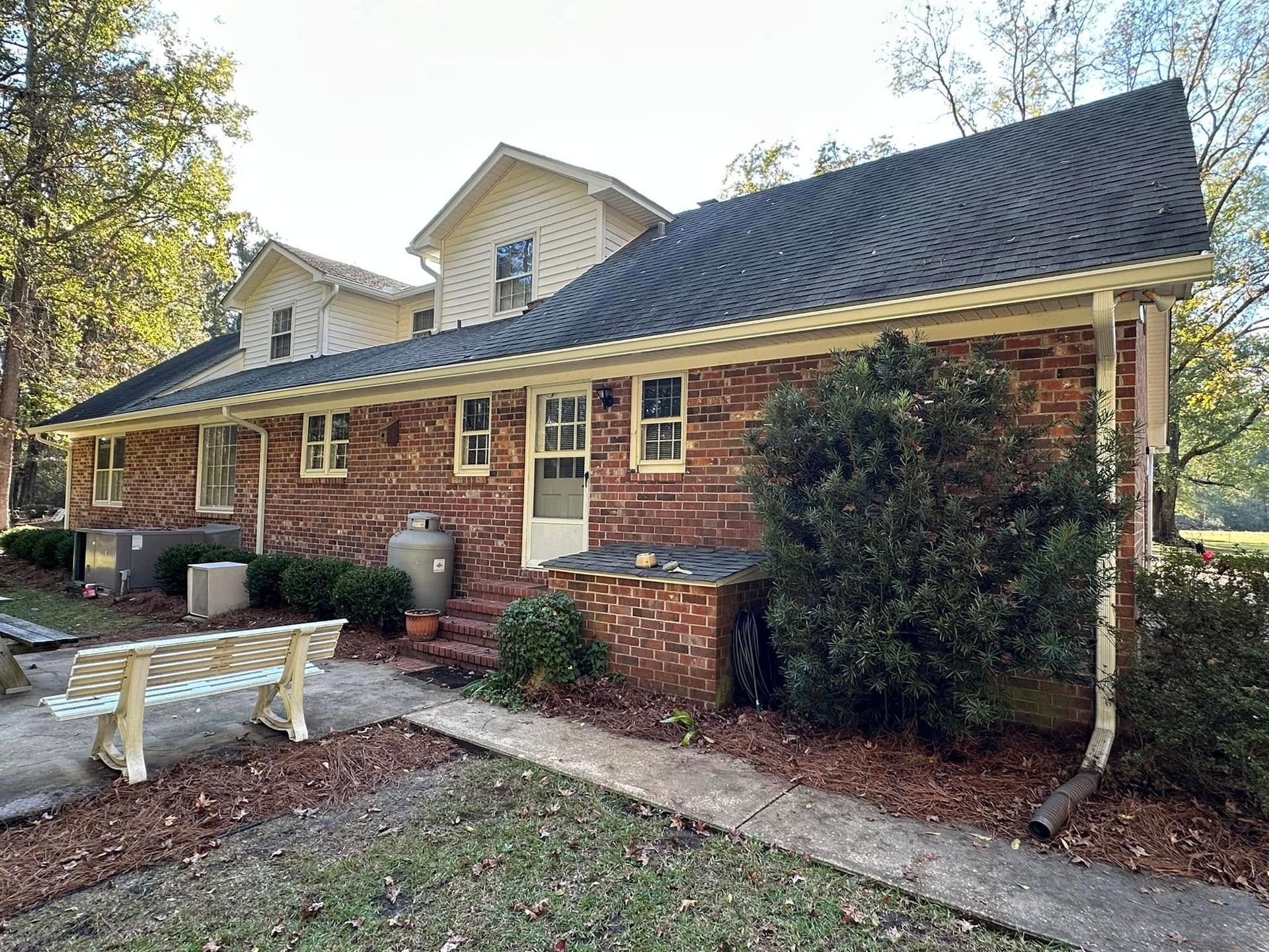 Brick house with dark roof, white trim, and landscaped front yard in daylight