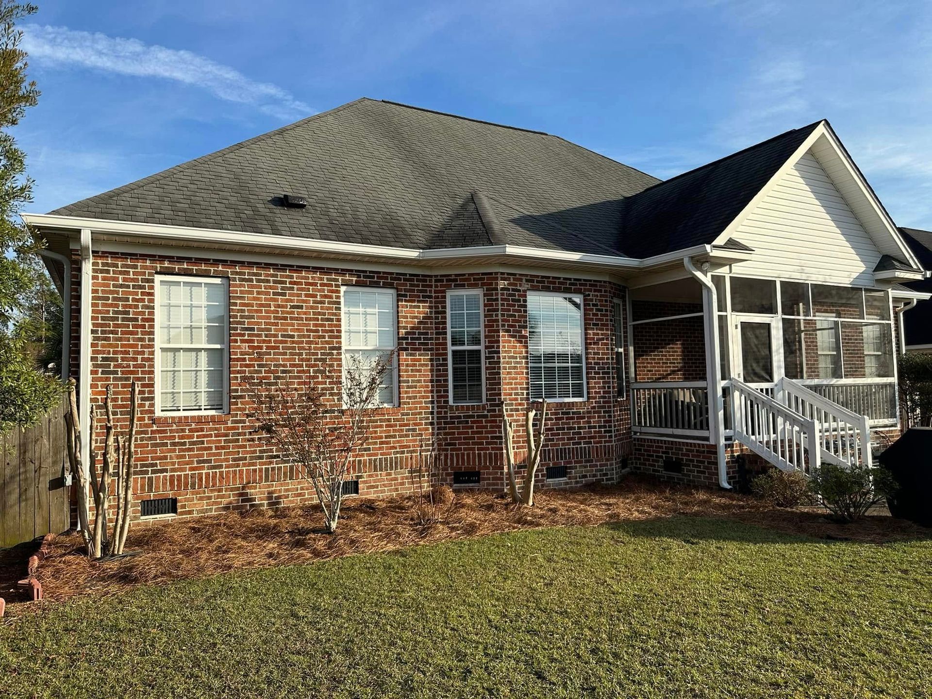 Brick house with gray roof and small white front porch on a grassy yard