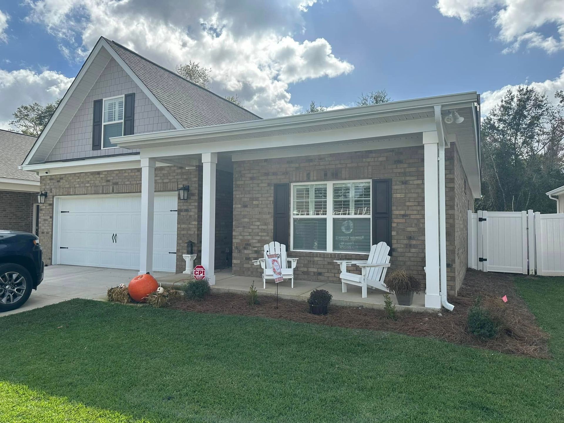 Suburban house with stone porch, white garage, and Halloween decorations on the front lawn.