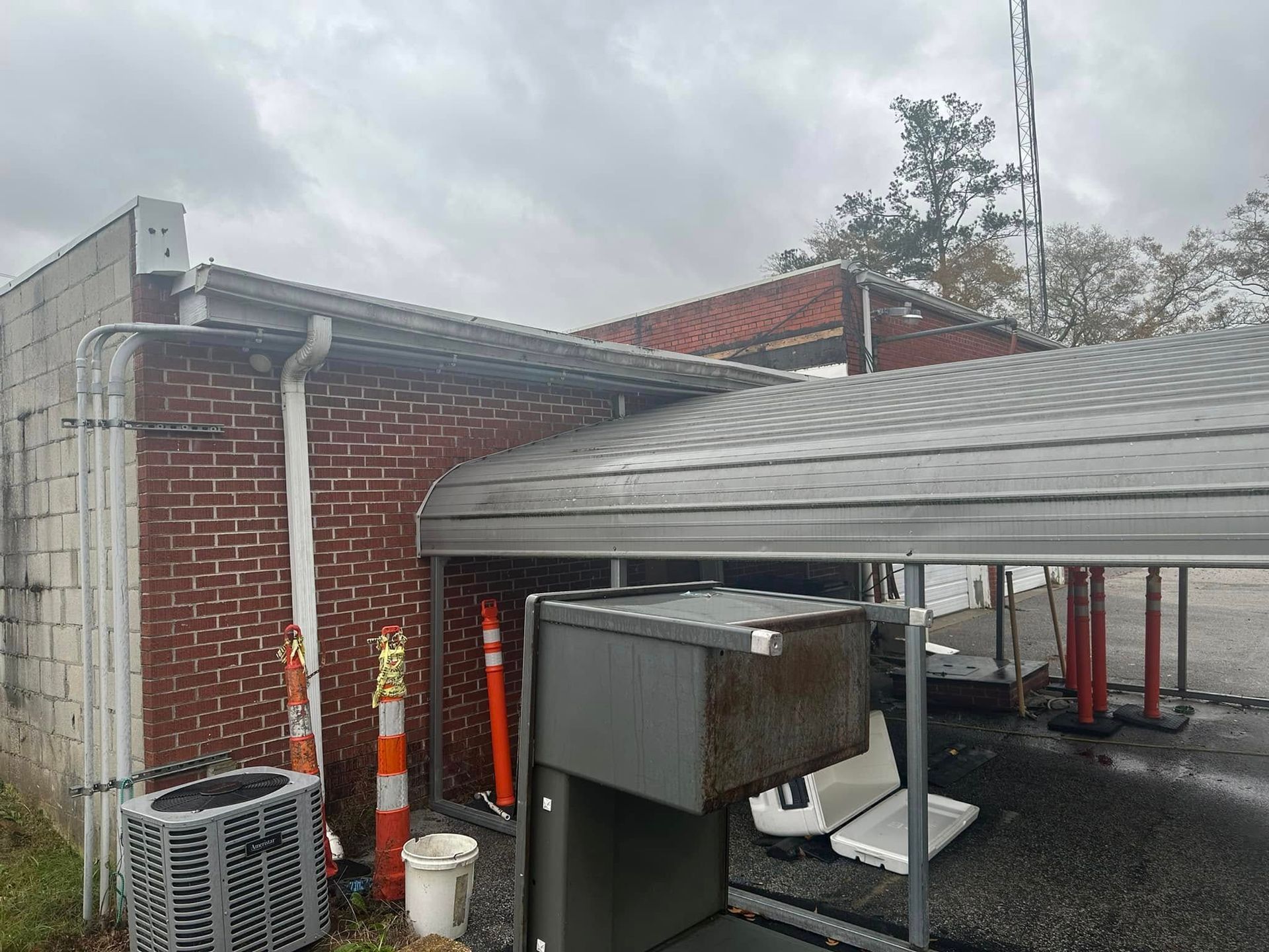 Outdoor utility area with brick wall, metal canopy, and industrial equipment in the foreground