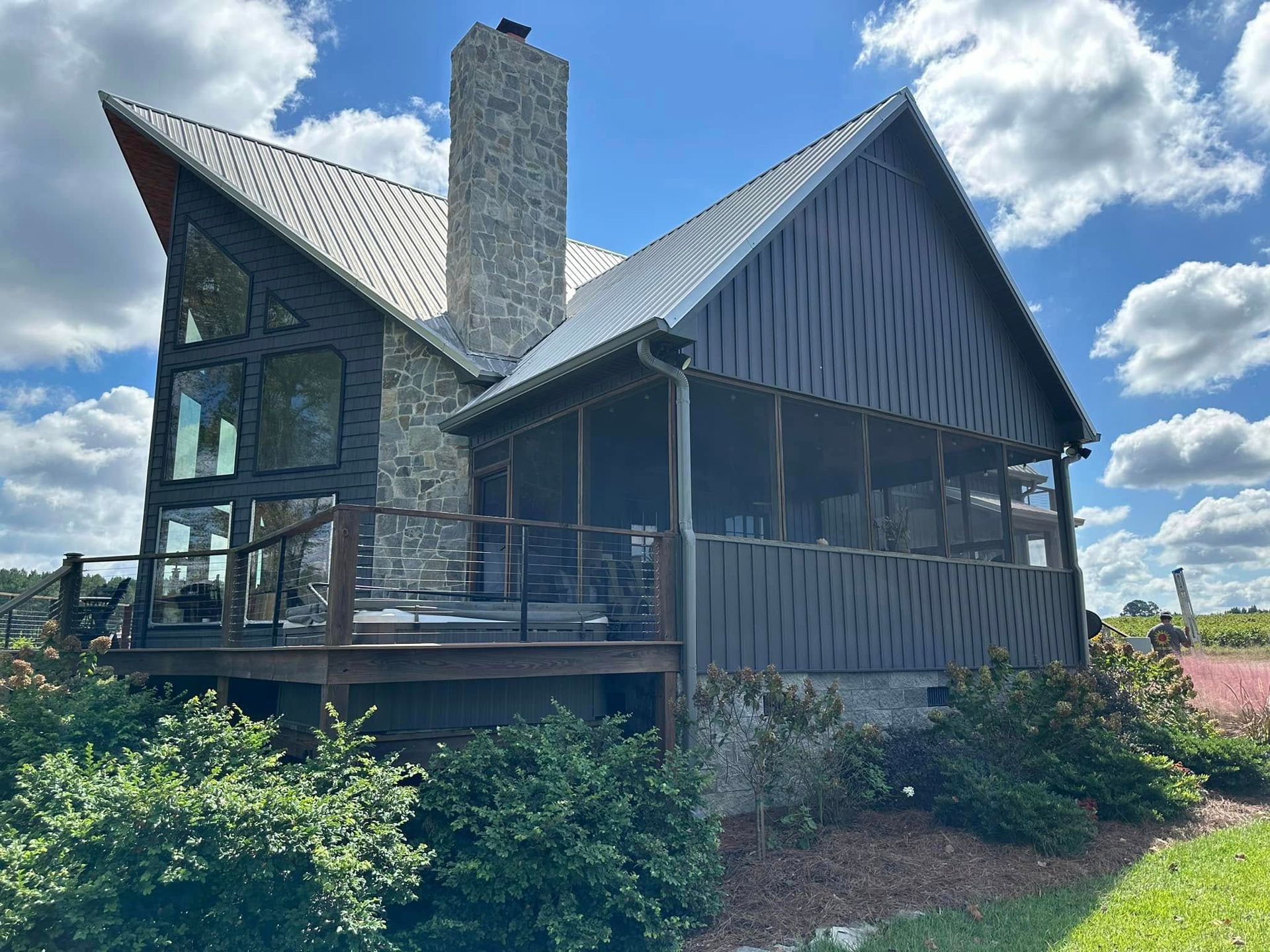 Rustic stone-and-wood house with steep roof and chimney on a sunny hillside under a blue sky