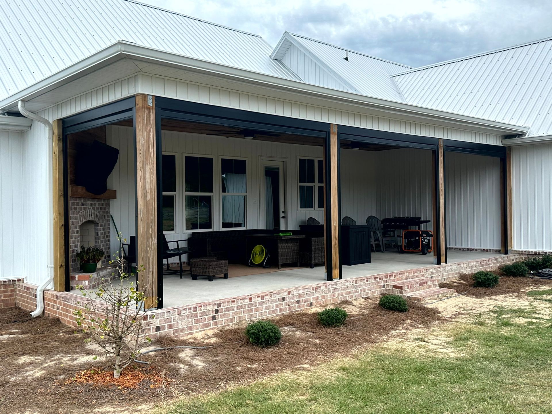 Covered front porch with white roof, wooden posts, and outdoor seating on a landscaped yard.