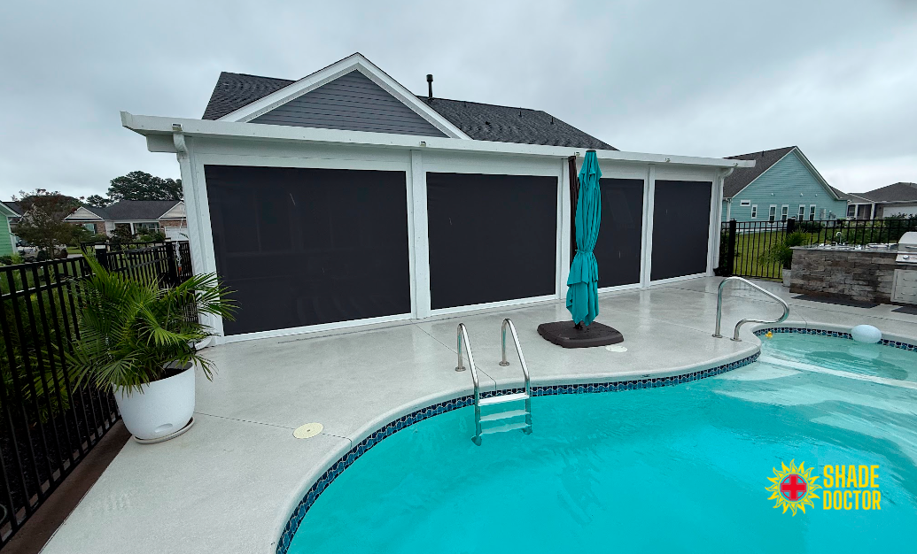 Backyard pool with white garage, turquoise umbrella, and black privacy screens.