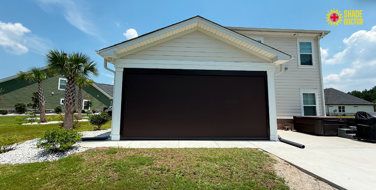 Suburban house with a two-car garage, white siding, and a driveway under a blue sky.