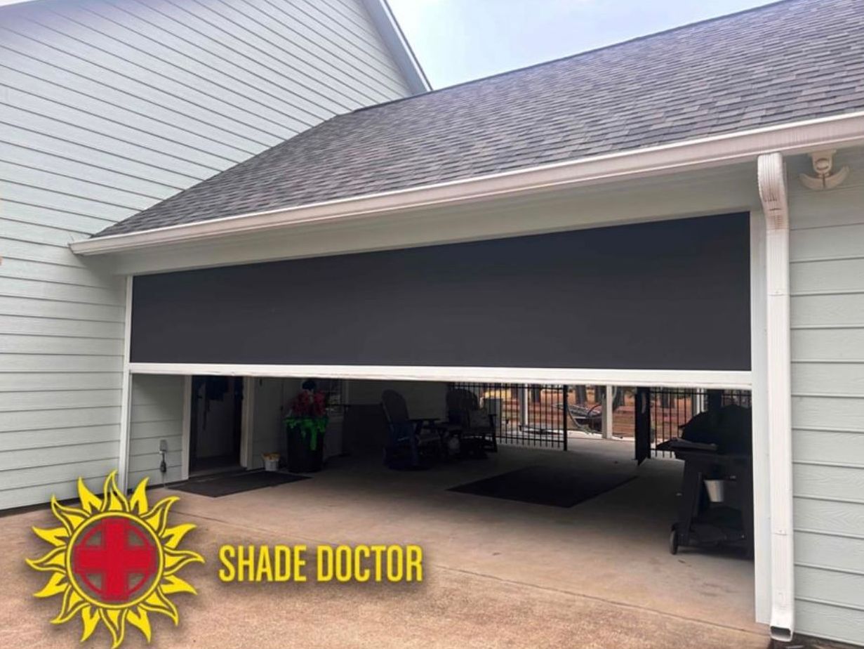 Partially open garage door with a black shade covering the top opening