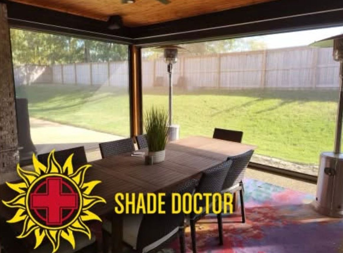 Covered patio with dining table and chairs overlooking a green backyard, with Shade Doctor logo