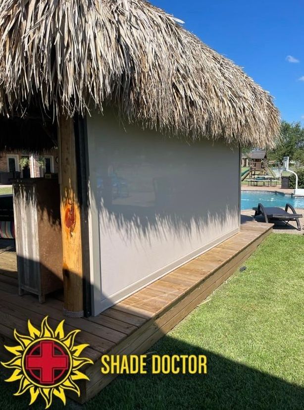 Thatched hut with white exterior beside a pool and lawn, with Shade Doctor logo at bottom.
