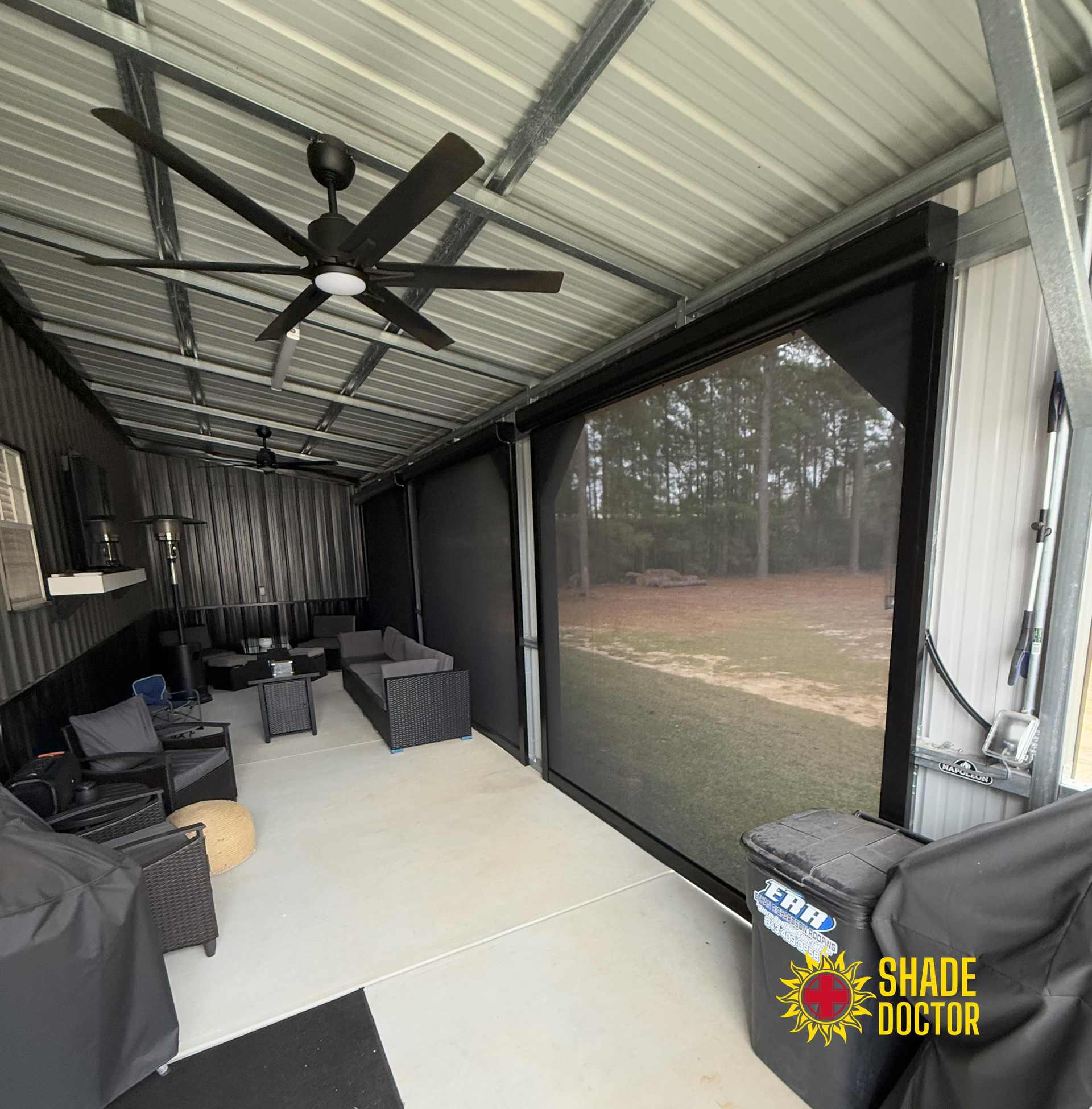Covered patio with black wicker seating, ceiling fans, and screened view of grassy yard.