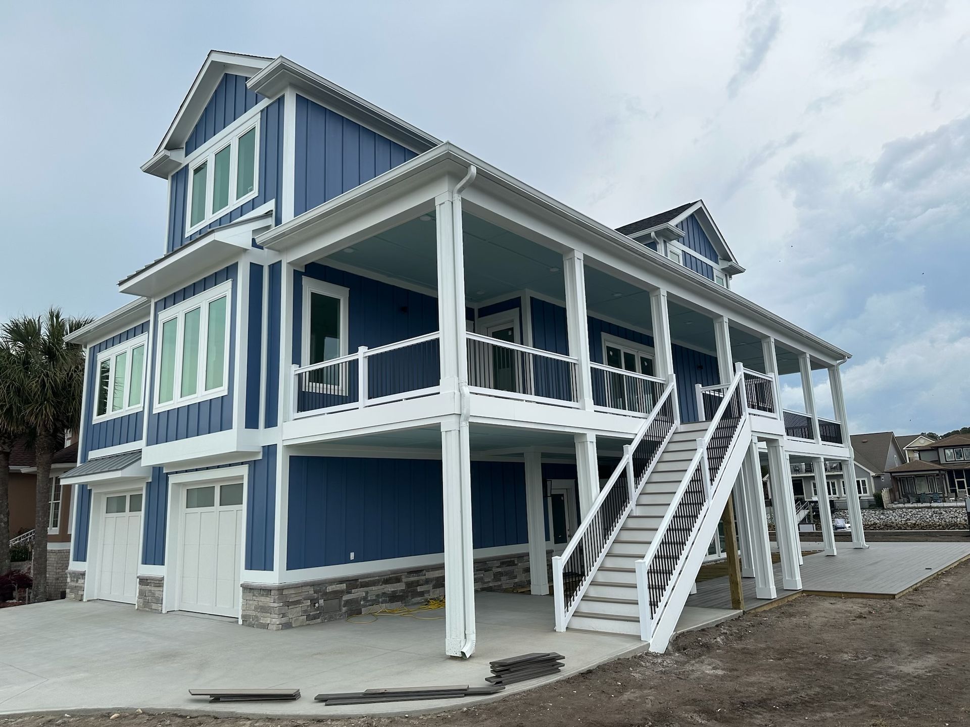 Blue two-story coastal house with white trim and exterior staircase on a raised foundation