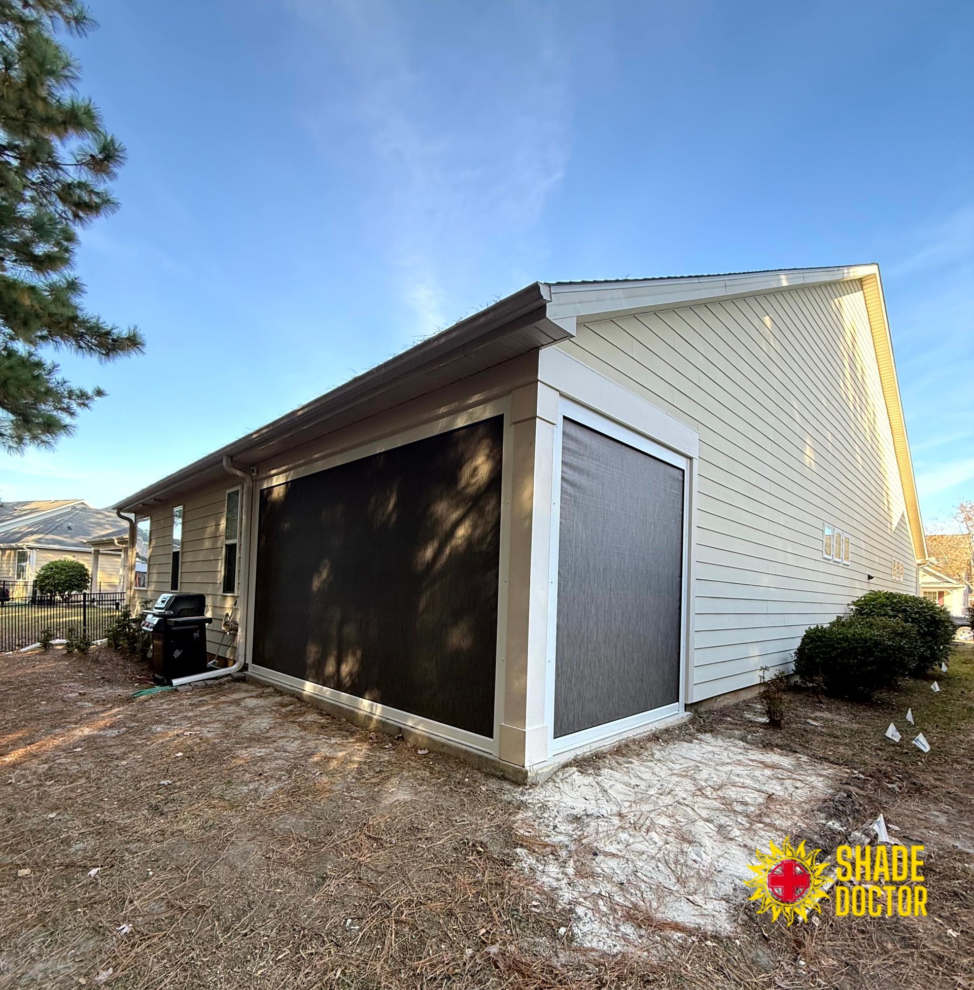 Detached house with screened porch and white siding beside a gravel yard in winter light