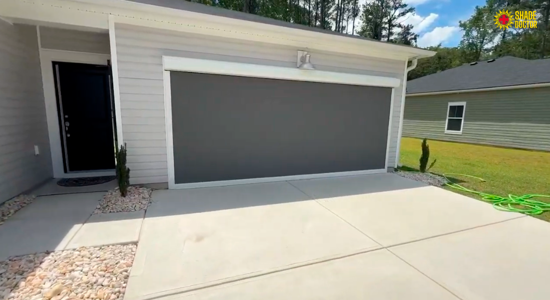 Modern gray house garage with closed door, white trim, and a concrete driveway in front.