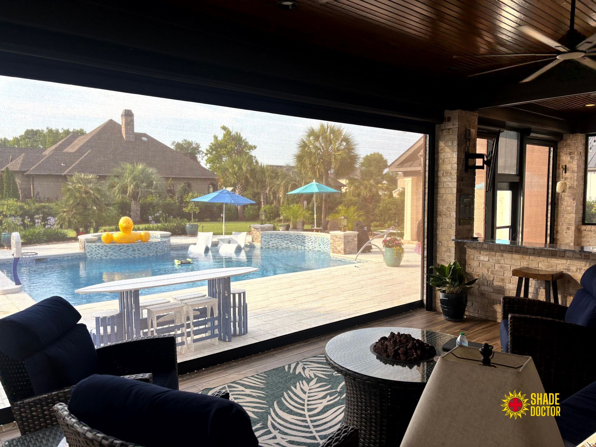 Covered patio overlooking a backyard pool with blue umbrellas and white patio furniture