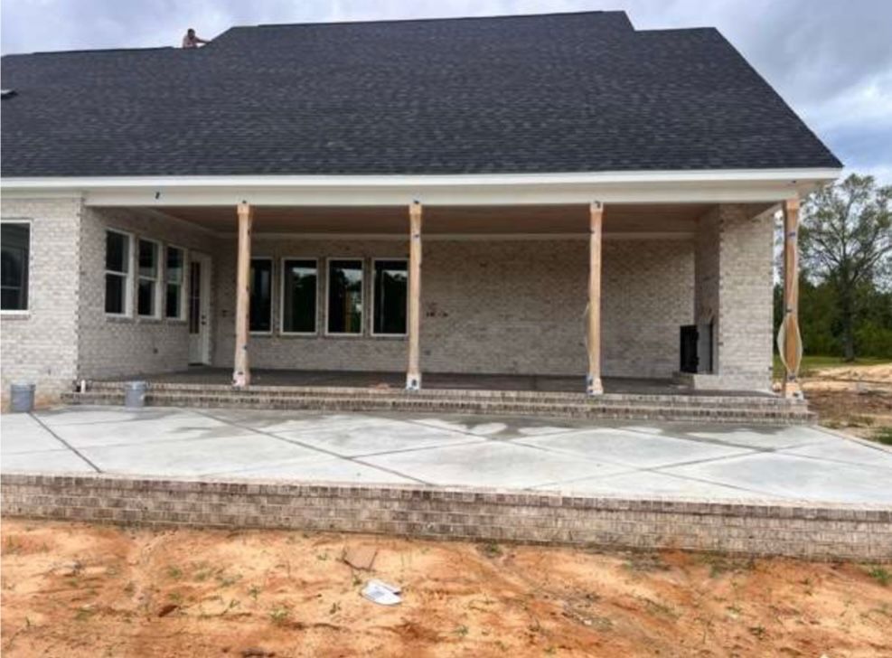 New brick house with covered front porch and concrete driveway under construction