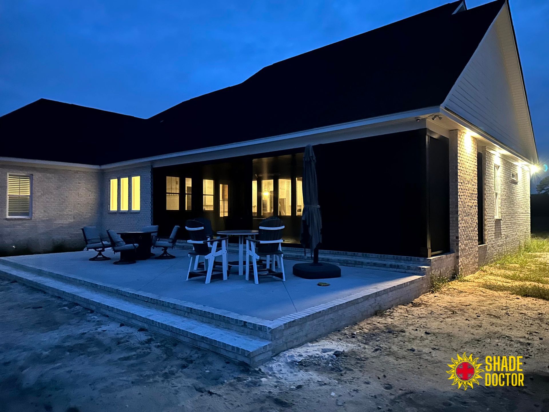 Modern house patio at dusk with outdoor dining table, warm lights, and a blue evening sky
