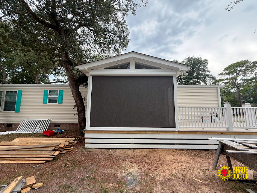 House exterior with a screened porch, white siding, and stacked lumber in the yard