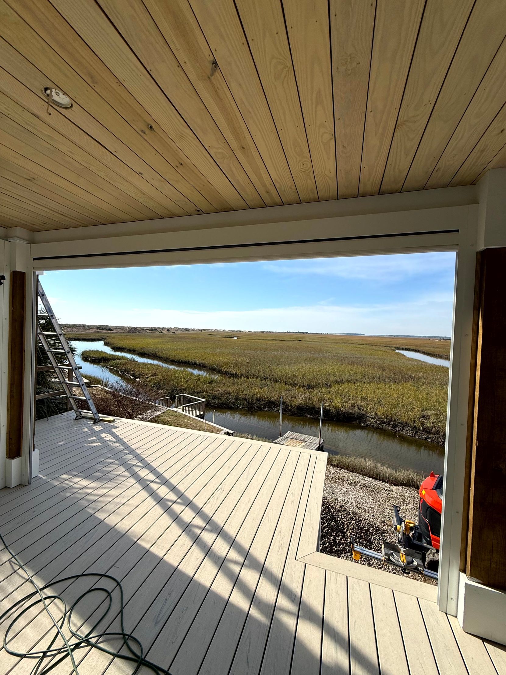 Porch overlooking marshland and water under a clear blue sky