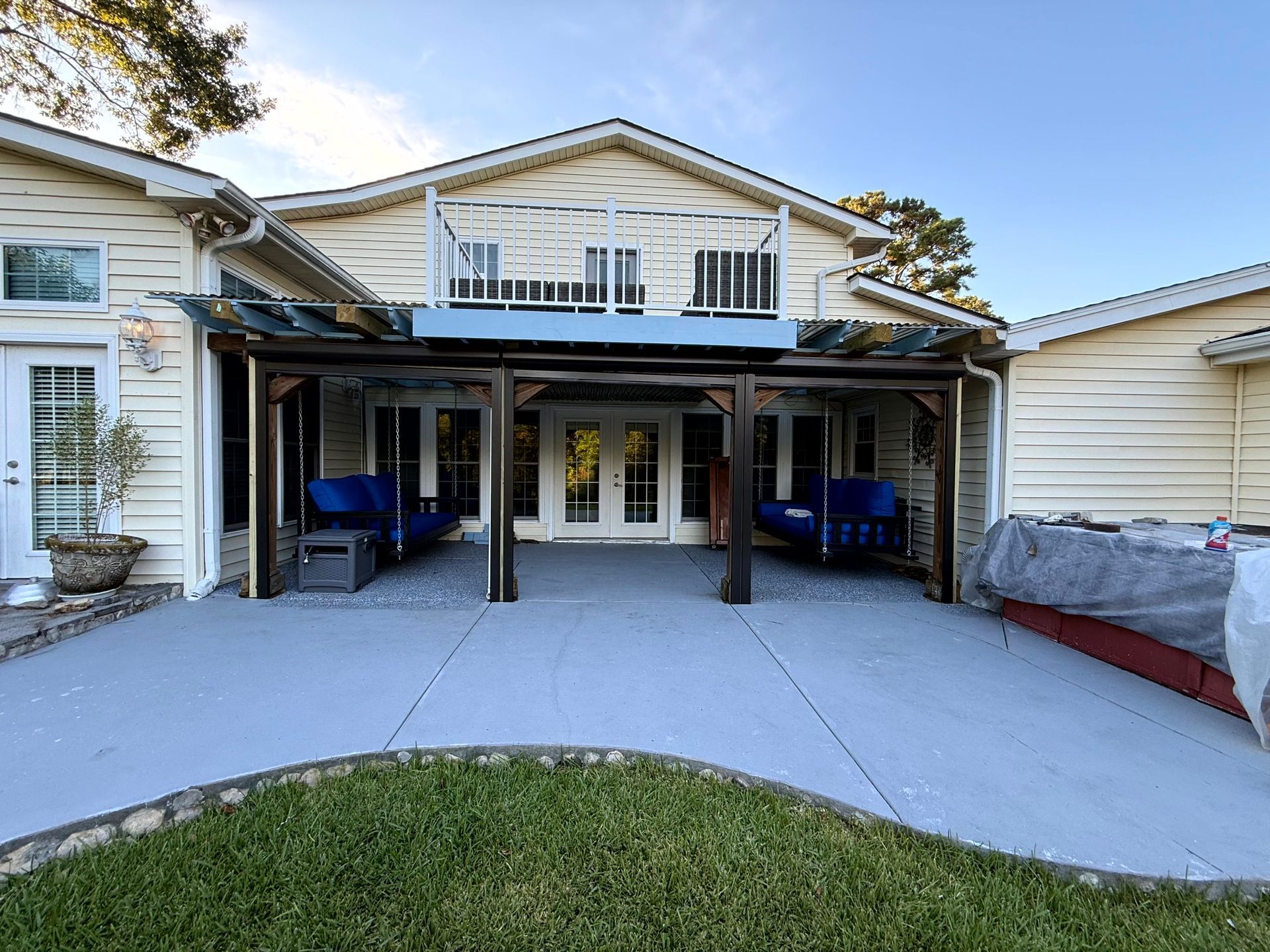 Front view of a house with a covered patio, white trim, and a concrete driveway under a blue sky