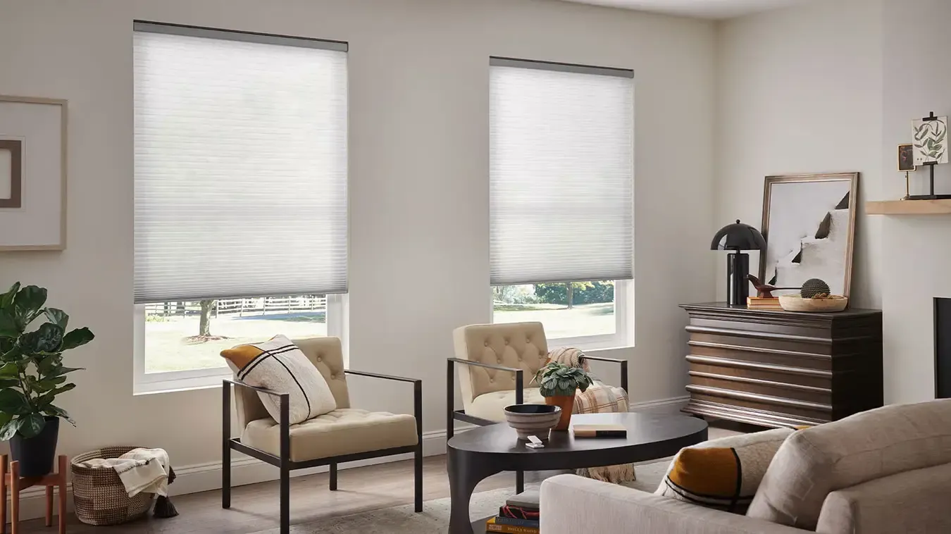 Bright living room with large windows, beige armchairs, coffee table, sofa, and dark dresser with mirror.