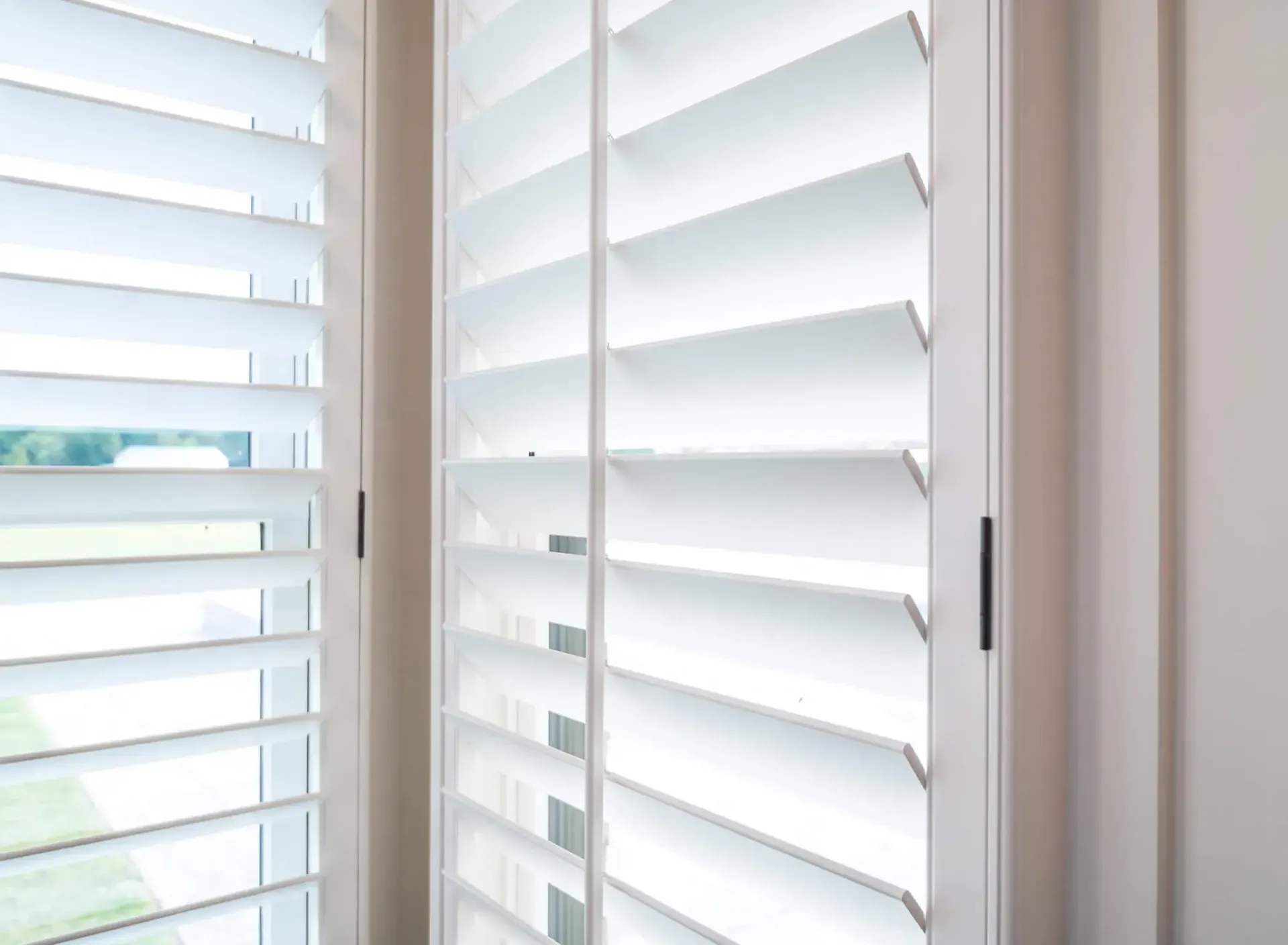 White window shutters with slats letting in daylight