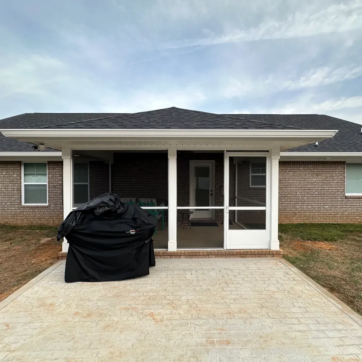 Single-story house with a covered front porch and white double doors, viewed from a paved driveway.