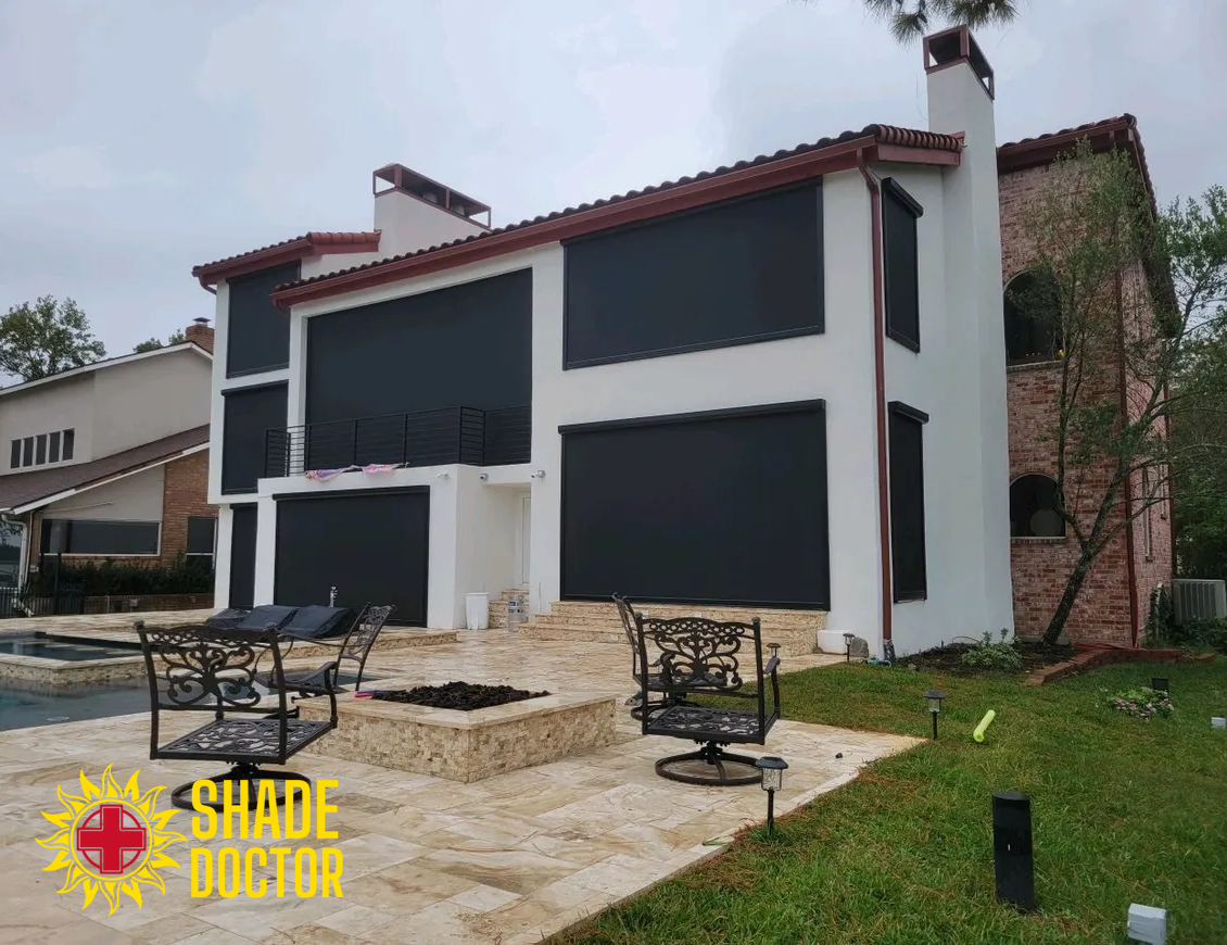 Modern two-story house with dark window shades and patio furniture in a backyard.