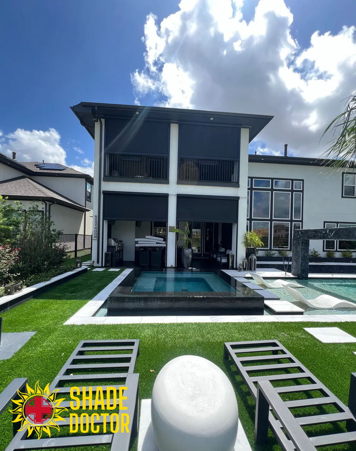 Modern two-story white house with pool, green lawn, and patio under a bright blue sky