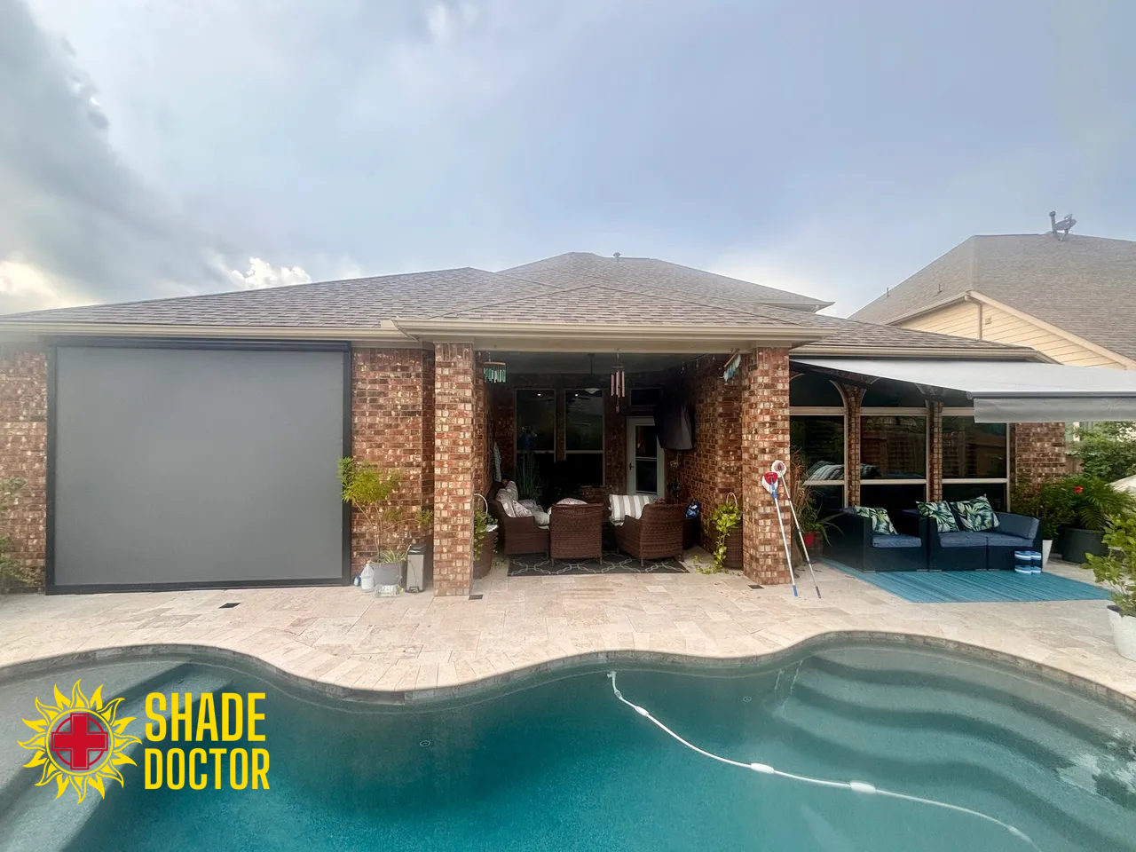 Backyard home with a covered patio, garage, and blue swimming pool in the foreground