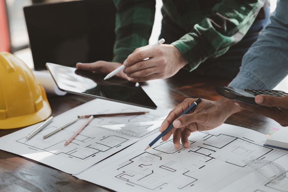 a group of people are sitting at a table looking at a blueprint .