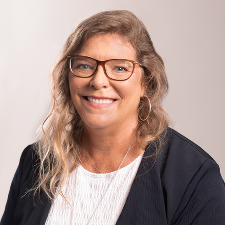 a photo of Debi Katsmar wearing glasses and hoop earrings smiles for the camera