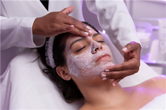 Facial treatment with white cream being applied to a woman’s face in a spa setting