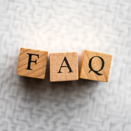 Wooden letter blocks spelling “FAQ” on a textured white surface