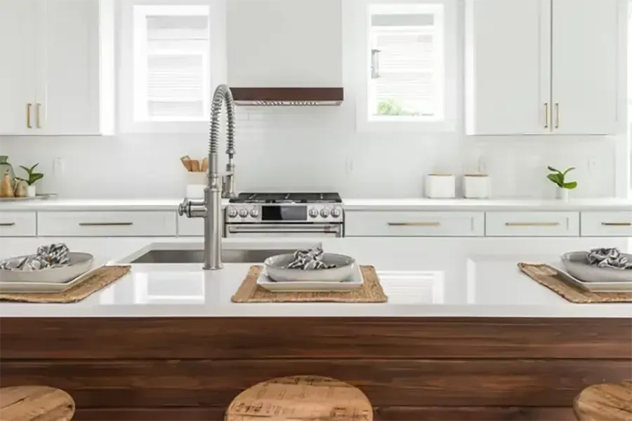 Bright white kitchen with wood island, stainless range, and set dining place settings