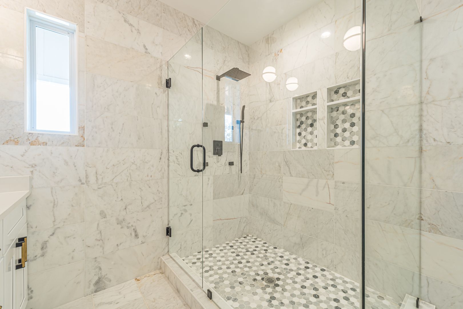 Bright marble walk-in shower with glass enclosure, rain showerhead, and mosaic tile floor