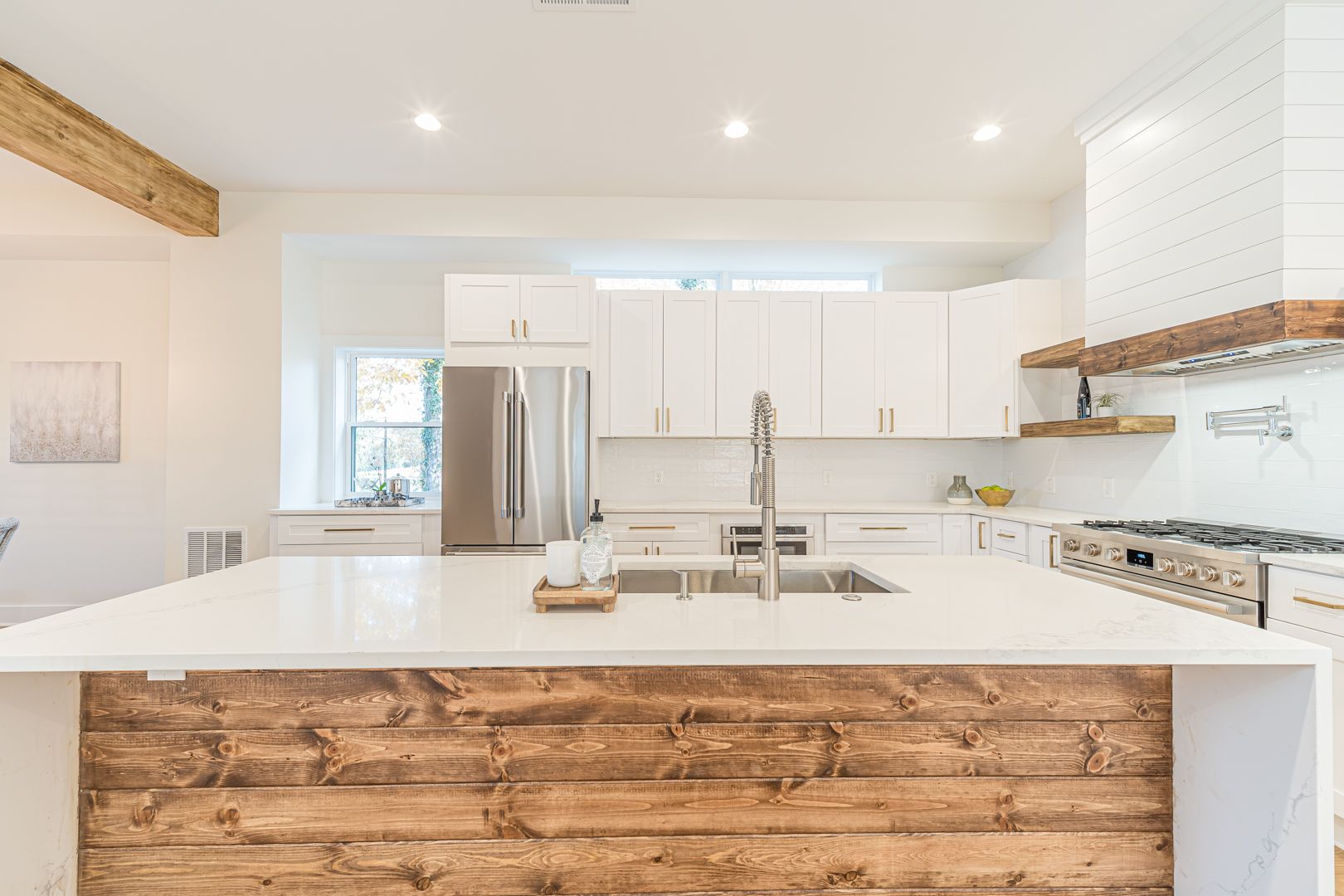 Bright modern kitchen with white cabinets, stainless appliances, and a large wood-front island