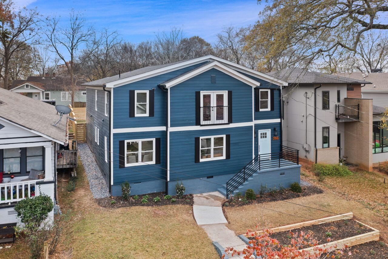 Blue two-story house with white trim and front steps in a leafy residential neighborhood
