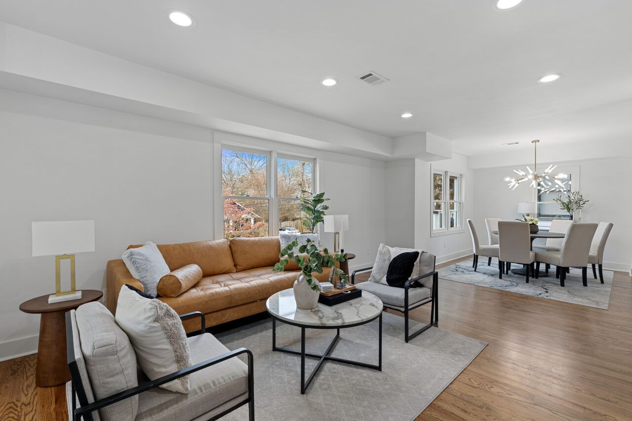 Bright modern living and dining room with tan sofa, gray chairs, and wood floors