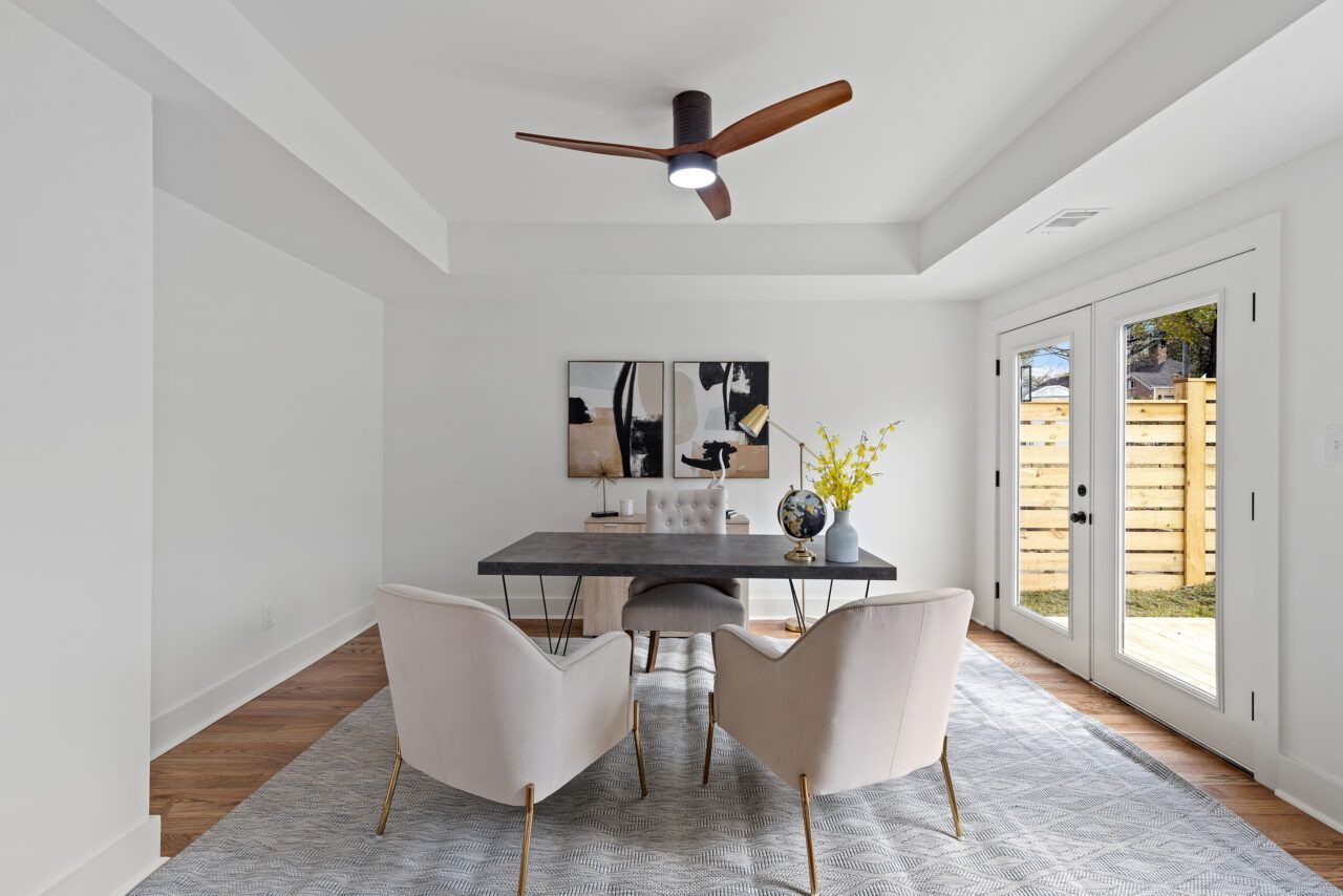 Modern dining room with a dark table, cream chairs, wall art, and French doors to a patio.