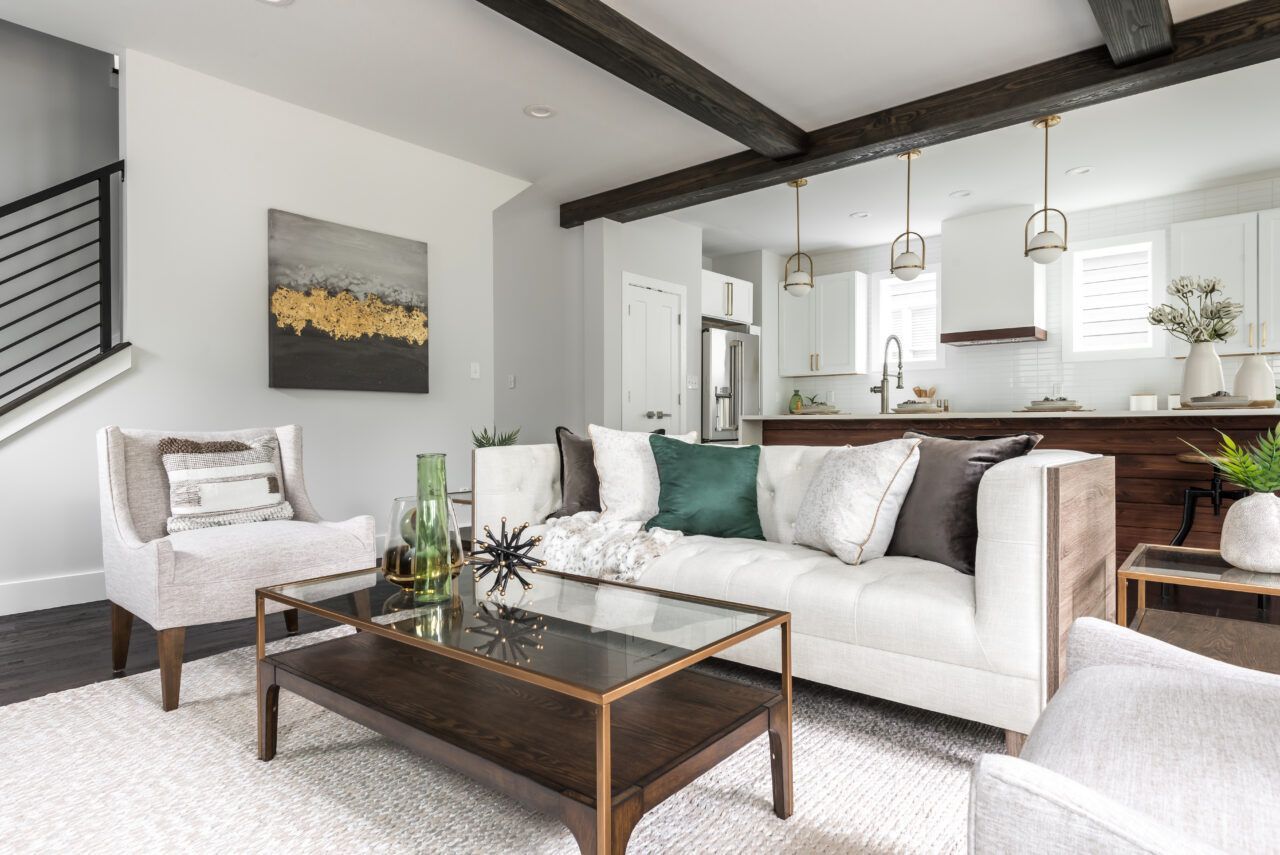 Modern living room with white sofa, glass coffee table, and open kitchen with exposed beams