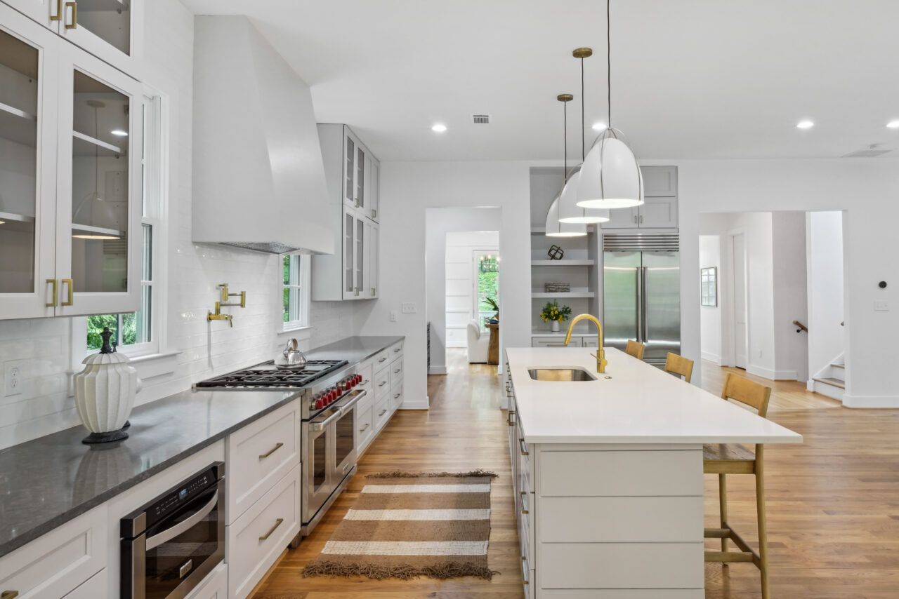 Bright modern kitchen with white cabinets, island, stainless appliances, and wood floors