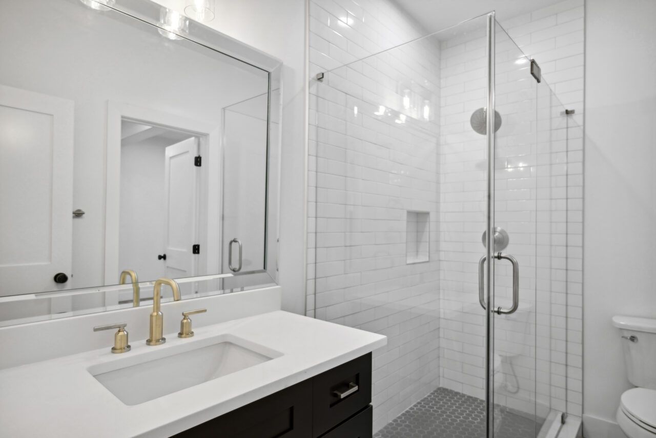 Modern white bathroom with vanity sink, mirror, and glass-enclosed shower