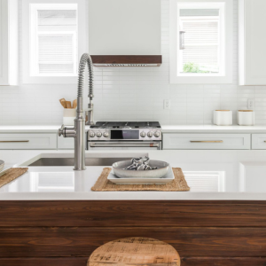 Bright white kitchen with a farmhouse sink, island, stove, and windows letting in daylight