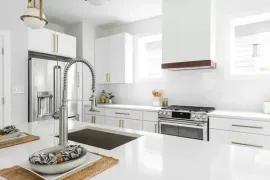 Bright white modern kitchen with stainless steel appliances and a central island sink