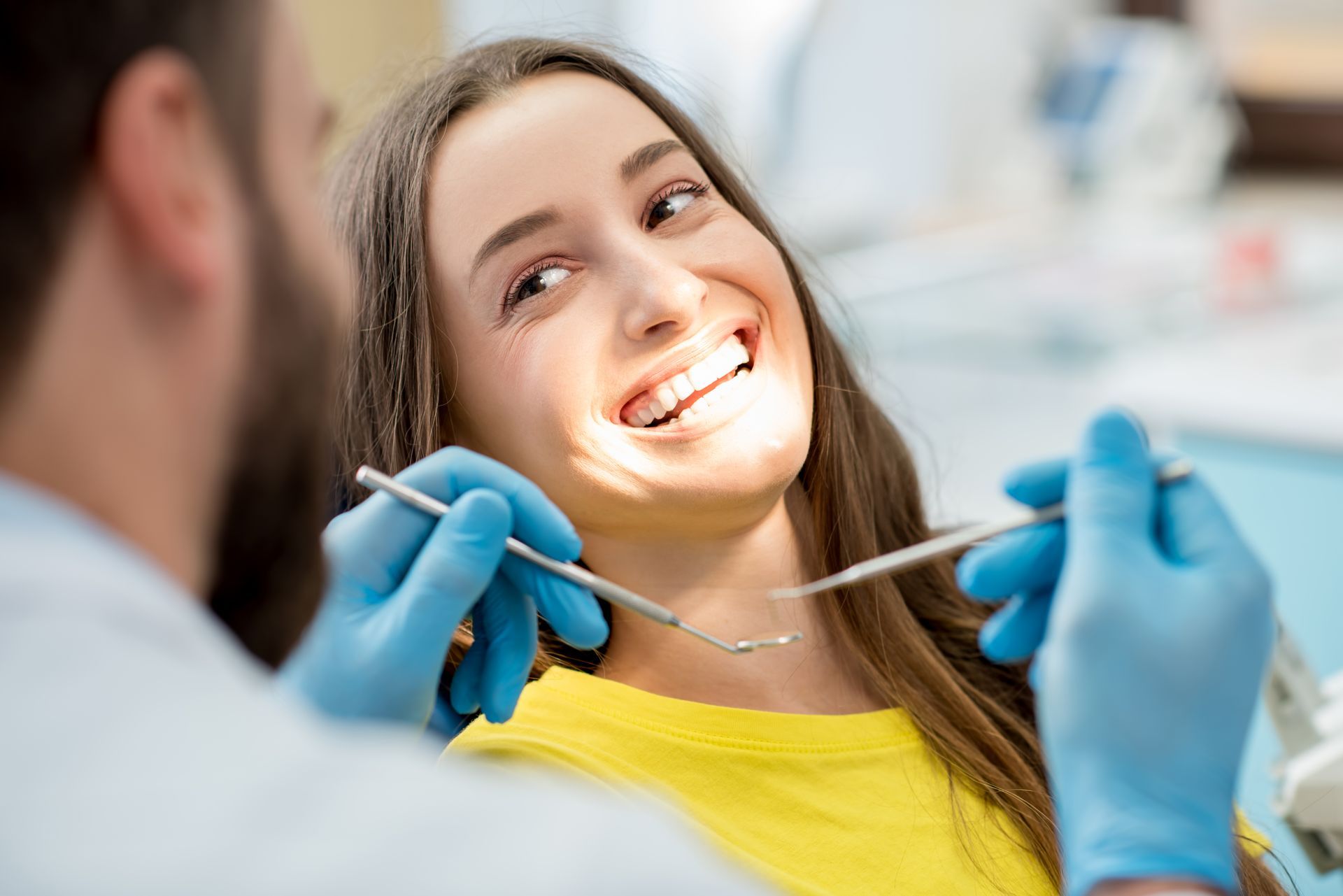 Dental professional in white coat and gloves performing a procedure on a patient. Dental professional in white coat and gloves performing a procedure on a patient.